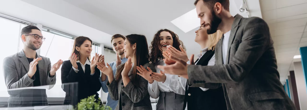 A group of employees cheering around a table